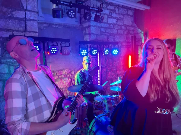 Professionelle Liveband mit Sängerin und Gitarrist bei einem energiegeladenen Live-Auftritt auf einer Veranstaltung in der Schweiz.